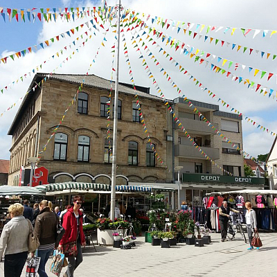 Ibbenbüren, Oberer Markt Oberer Markt in Ibbenbüren. Bunte Fähnchen hängen an einem Masten und Menschen machen einen Einkaufsbummel durch die Stadt